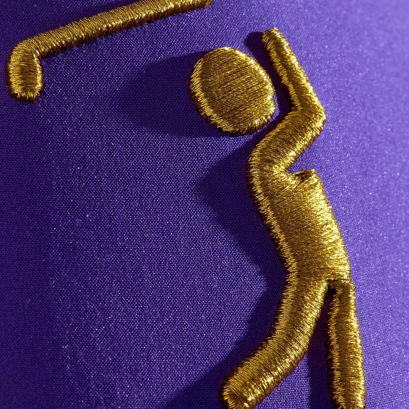 Gold embroidered figure on a purple fabric background