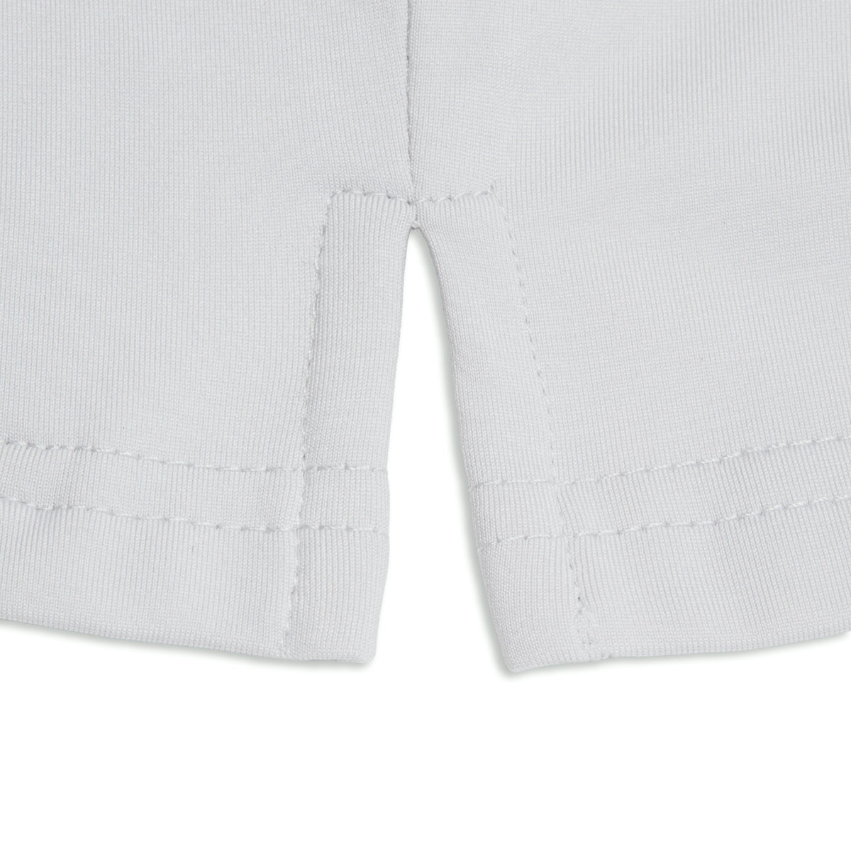 Close-up of the Bone - Hoodie’s white hem featuring a small center slit, reminiscent of athletic shorts. The fabric appears smooth and slightly stretchy, ideal for moisture wicking during active wear. Double stitching is visible along the hem and slit edges, creating a clean, finished look. The background is plain white.