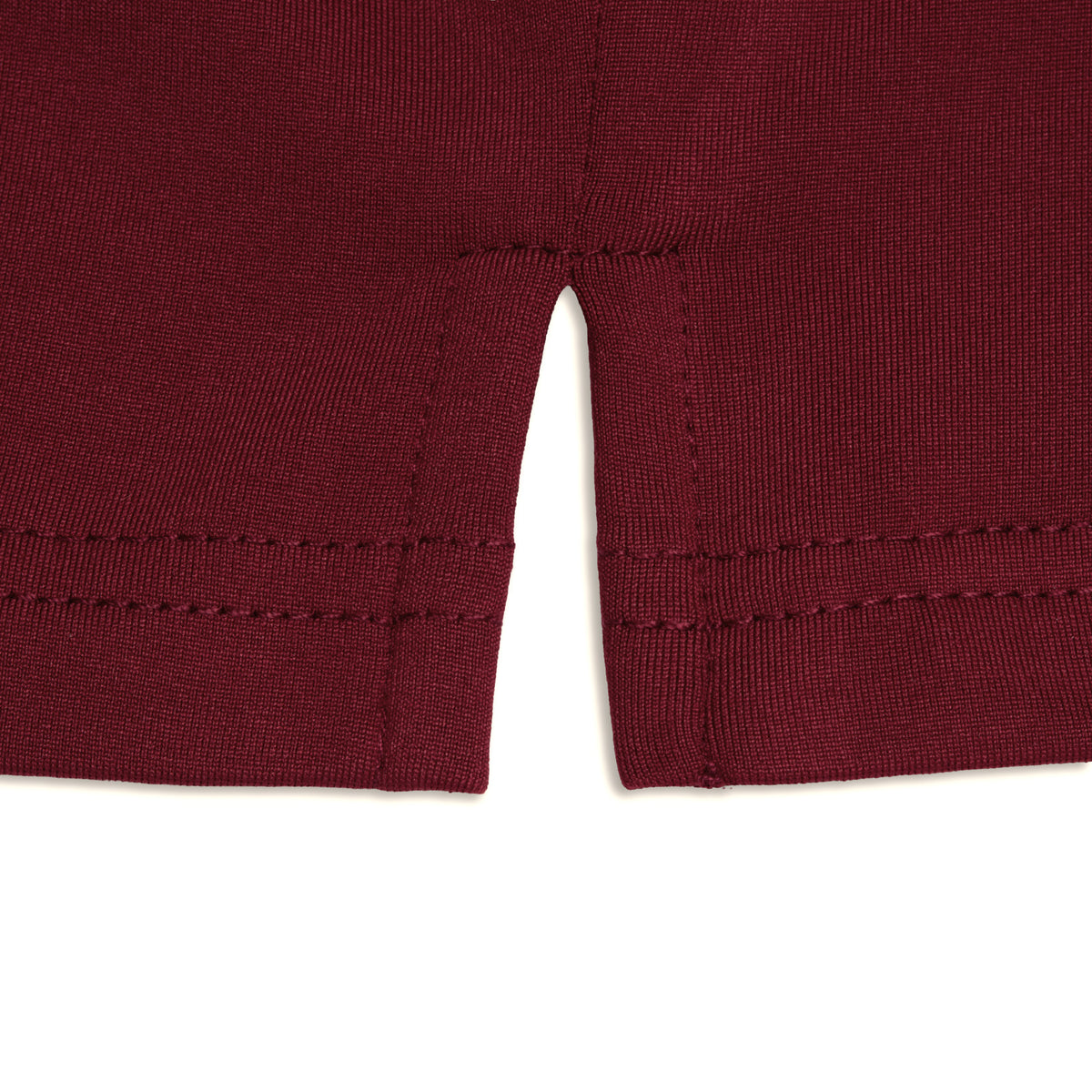Close-up of the hem of the Burgundy Hoodie, showing a small center slit in the maroon fabric. The stitching is visible, with clean, straight seams and a double-row of stitches along the edge against a white background. Designed for performance, this hoodie features moisture-wicking fabric to keep you comfortable and dry.