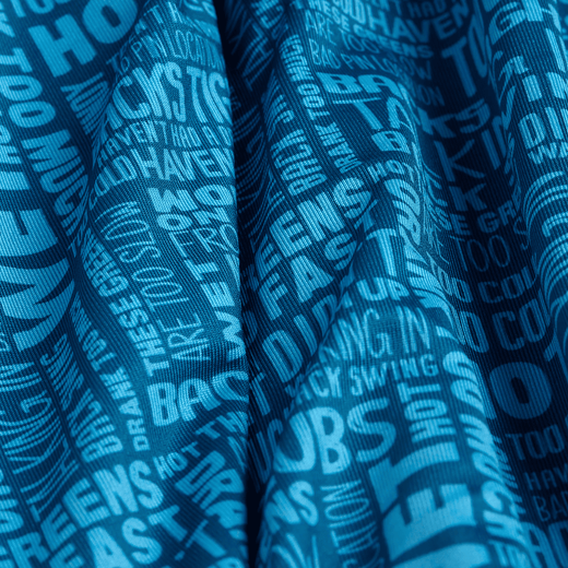 Blue fabric with bold white text in various fonts and sizes, including phrases like BAGS AND, JOBS AND, and FAST. The fabric is draped, creating shadows and waves across the surface. The text overlaps and curves slightly with the folds.