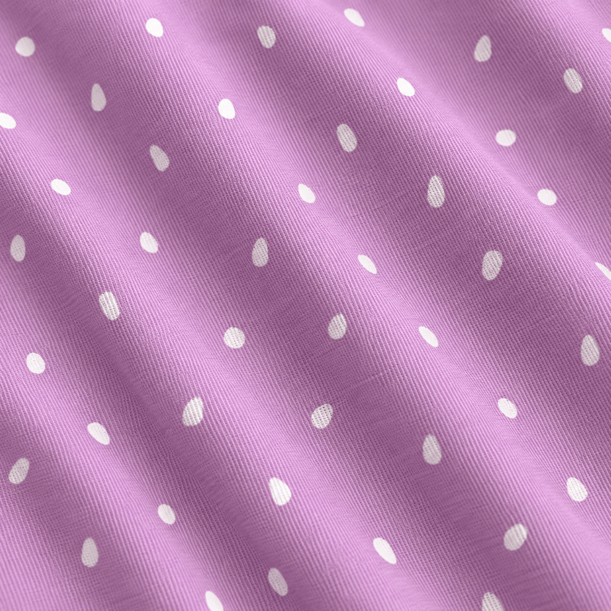 A close-up, angled view of the Tickleberry Tidbits - Polo showcases its light purple cotton fabric, adorned with a repeating pattern of small, white, slightly elongated teardrop or egg-shaped dots. The material reveals visible diagonal textile weave lines and gentle, natural folds that cast subtle shadows across the surface. Designed with moisture-wicking properties, the Tickleberry Tidbits - Polo helps keep you comfortable and dry throughout the day.