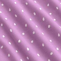 A close-up, angled view of the Tickleberry Tidbits - Polo showcases its light purple cotton fabric, adorned with a repeating pattern of small, white, slightly elongated teardrop or egg-shaped dots. The material reveals visible diagonal textile weave lines and gentle, natural folds that cast subtle shadows across the surface. Designed with moisture-wicking properties, the Tickleberry Tidbits - Polo helps keep you comfortable and dry throughout the day.