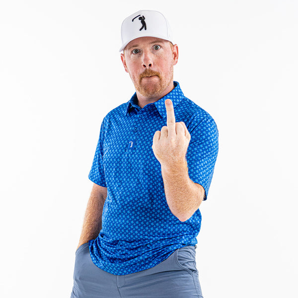 A man in a Bogey Bros Birdie Finger - Blue Jay - Polo, gray shorts, and a white hat extends his middle finger to the camera with a surprised look. He has reddish hair, a mustache, and stands against a plain white background.