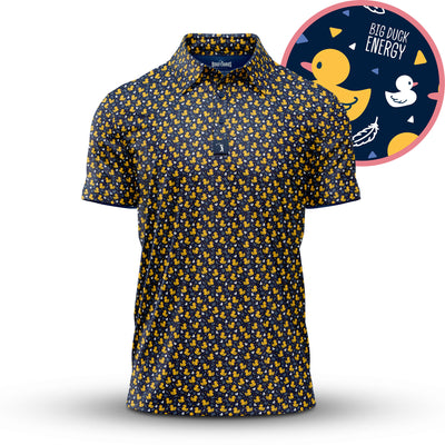 The “Big Duck Energy - Polo” is a navy athletic-fit shirt featuring a repeating yellow rubber duck pattern, with close-up insets highlighting playful ducks, leaves, waves, and “BIG DUCK ENERGY” text on a dark background.