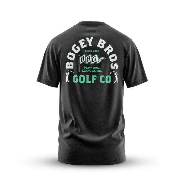 The Flagship - T-Shirt: An athletic-fit dark gray jersey tee, shown from the back with a large white and green BOGEY BROS GOLF CO graphic, "SINCE 2020," "PLAY BAD, LOOK GOOD," and a cartoon golf ball with crossed tees. Made from stretchy, comfortable fabric.